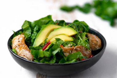 Siyah kasede avokadolu tavuk salatası. Sağlıklı yemek.