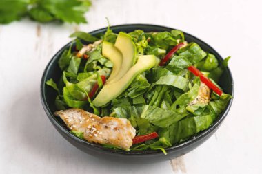 Sağlıklı sebze salatası, kızarmış tavuk, avokado, biber ve beyaz tabakta yaprak salatası..