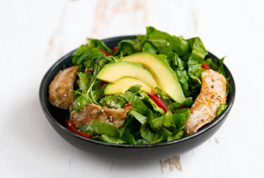 Sağlıklı sebze salatası, kızarmış tavuk, avokado, biber ve beyaz tabakta yaprak salatası..