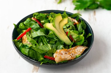 Siyah kasede avokadolu tavuk salatası. Sağlıklı yemek.