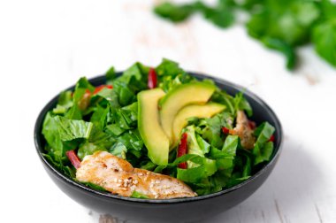 Sağlıklı sebze salatası, kızarmış tavuk, avokado, biber ve beyaz tabakta yaprak salatası..