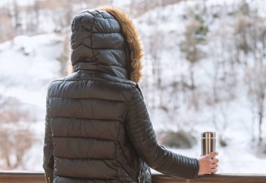 Bir termos kahve veya çay kışın balkondan onun elinde bir kış ceket bir kız