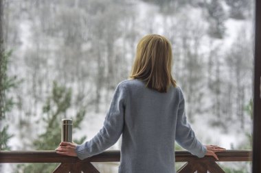 Kadın bir termos şişe elinde bir kış ormanda arka planda