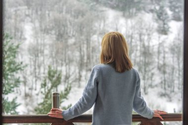 Kadın bir termos şişe elinde bir kış ormanda arka planda