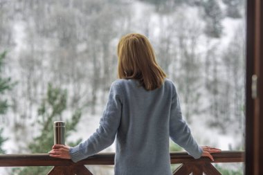 Kadın bir termos şişe elinde bir kış ormanda arka planda