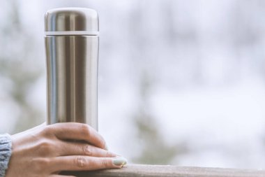 Kadın bir termos şişe elinde bir kış ormanda arka planda