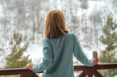 Kadın bir termos şişe elinde bir kış ormanda arka planda