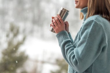 Kadın bir termos şişe elinde bir kış ormanda arka planda