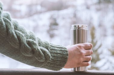 Adam elinde bir termos şişe bir kış ormanda arka planda