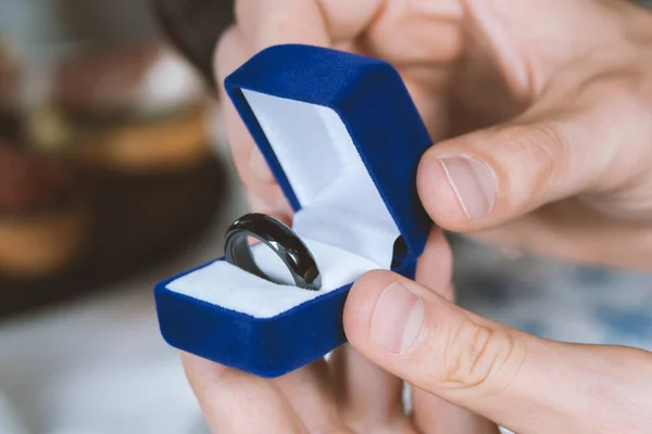 Male hands with blue velvet box containing payments smart ring. Man gives a woman payments smart ring.  Romantic dinner. Valentine day