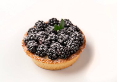 Taze böğürtlenli tatlı tart ve beyaz arka planda nane.