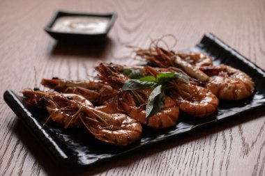 Siyah bir tabakta soslu ızgara kaplan karidesi..