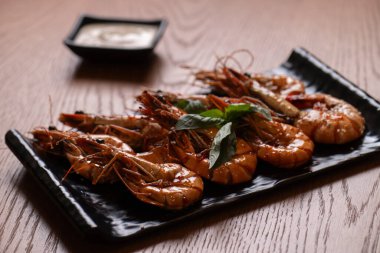 Siyah bir tabakta soslu ızgara kaplan karidesi..