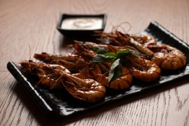 Siyah bir tabakta soslu ızgara kaplan karidesi..