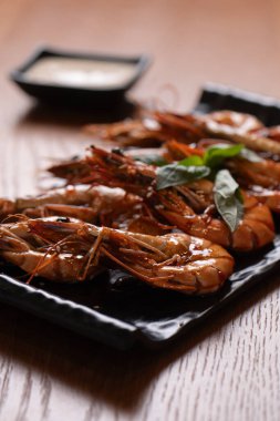Siyah bir tabakta soslu ızgara kaplan karidesi..