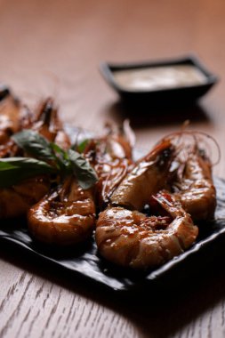 Siyah bir tabakta soslu ızgara kaplan karidesi..