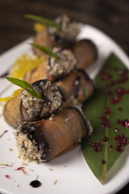 Beyaz bir tabakta fırında patlıcan rulosu. .