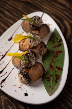 Beyaz bir tabakta fırında patlıcan rulosu. .