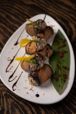 Beyaz bir tabakta fırında patlıcan rulosu. .