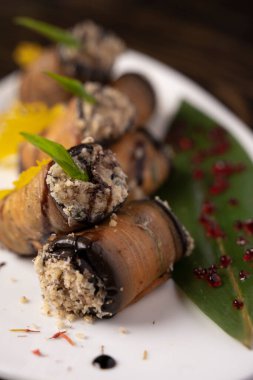 Beyaz bir tabakta fırında patlıcan rulosu. .