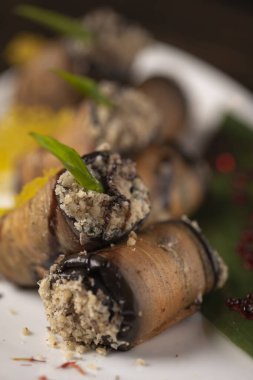 Beyaz bir tabakta fırında patlıcan rulosu. .