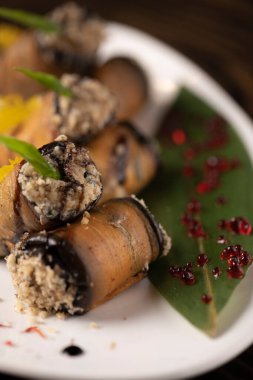 Beyaz bir tabakta fırında patlıcan rulosu. .