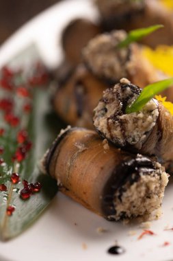 Beyaz bir tabakta fırında patlıcan rulosu. .