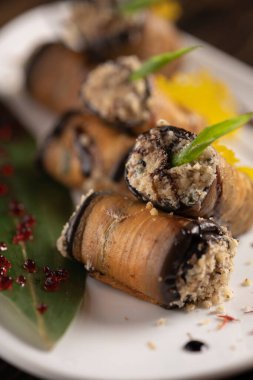 Beyaz bir tabakta fırında patlıcan rulosu. .