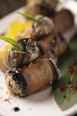 Beyaz bir tabakta fırında patlıcan rulosu. .