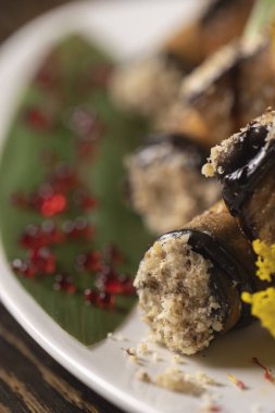 Beyaz bir tabakta fırında patlıcan rulosu. .