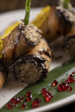 Beyaz bir tabakta fırında patlıcan rulosu. .