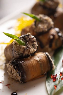 Beyaz bir tabakta fırında patlıcan rulosu. .