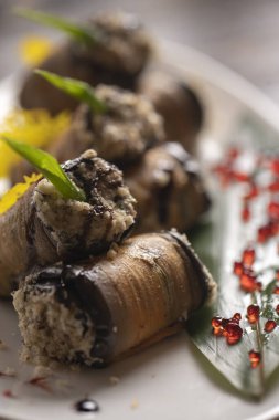 Beyaz bir tabakta fırında patlıcan rulosu. .