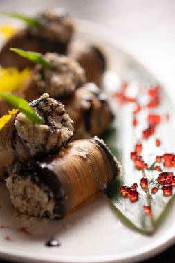 Beyaz bir tabakta fırında patlıcan rulosu. .