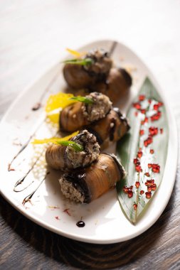 Beyaz bir tabakta fırında patlıcan rulosu. .