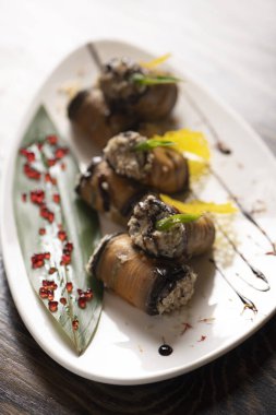 Beyaz bir tabakta fırında patlıcan rulosu. .