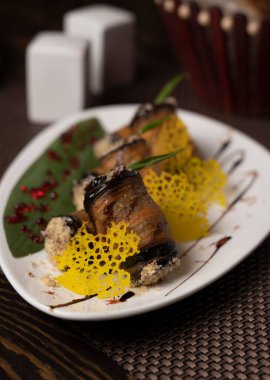 Beyaz bir tabakta fırında patlıcan rulosu. .