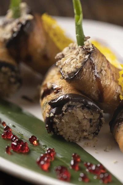 Beyaz bir tabakta fırında patlıcan rulosu. .