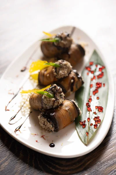 Beyaz bir tabakta fırında patlıcan rulosu. .