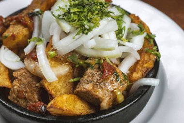 Beef stew with potatoes, carrots and herbs on black background with copy