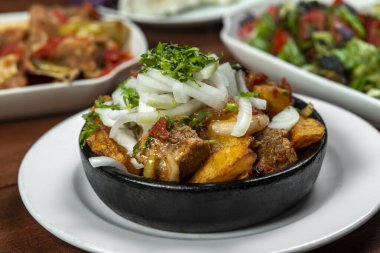 Beef stew with potatoes, carrots and herbs on black background with copy
