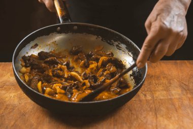 Aşçı eti sebzeli ve soğanlı bir kasede hazırlar. Doğu mutfağı.