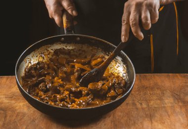 Aşçı eti sebzeli ve soğanlı bir kasede hazırlar. Doğu mutfağı.