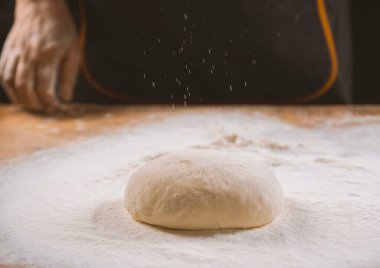 Hamur yoğurma fırını. Aşçı ahşap masada turta pişirmek için hamur yapıyor. İşlem hazırlığı ev yapımı hamur işi. Makarna, ekmek, spagetti, khachapuri, yemek konsepti.