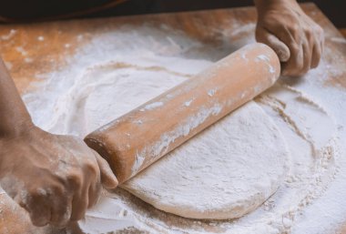 Pizza hazırlamak için hamur yoğuruyorum. Aşçı ahşap masada turta pişirmek için hamur yapıyor. İşlem hazırlığı ev yapımı hamur işi. Makarna, ekmek, spagetti, khachapuri, yemek konsepti.