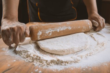 Pizza hazırlamak için hamur yoğuruyorum. Aşçı ahşap masada turta pişirmek için hamur yapıyor. İşlem hazırlığı ev yapımı hamur işi. Makarna, ekmek, spagetti, khachapuri, yemek konsepti.