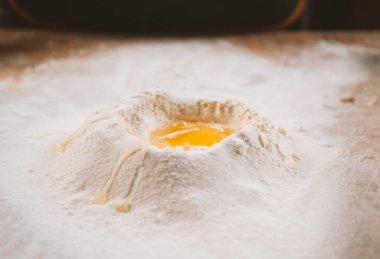 Üzerinde yumurta sarısı olan bir un yığınını kapat.