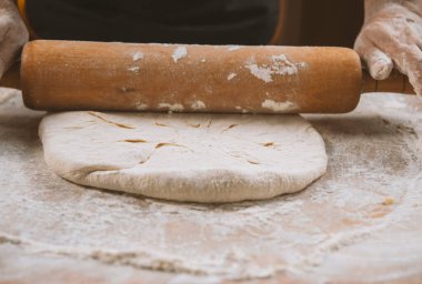 Pizza hazırlamak için hamur yoğuruyorum. Aşçı ahşap masada turta pişirmek için hamur yapıyor. İşlem hazırlığı ev yapımı hamur işi. Makarna, ekmek, spagetti, khachapuri, yemek konsepti.