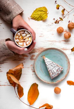 Pasta, ceviz ve saçılmış yapraklarla, sonbahar kompozisyonu eşliğinde eski püskü bir masada lokum tutan kadınların üst görüntüsü.
