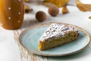 Kurumuş yapraklar ve sonbahar kompozisyonu ile sıcak çayla servis edilen fırında turta.